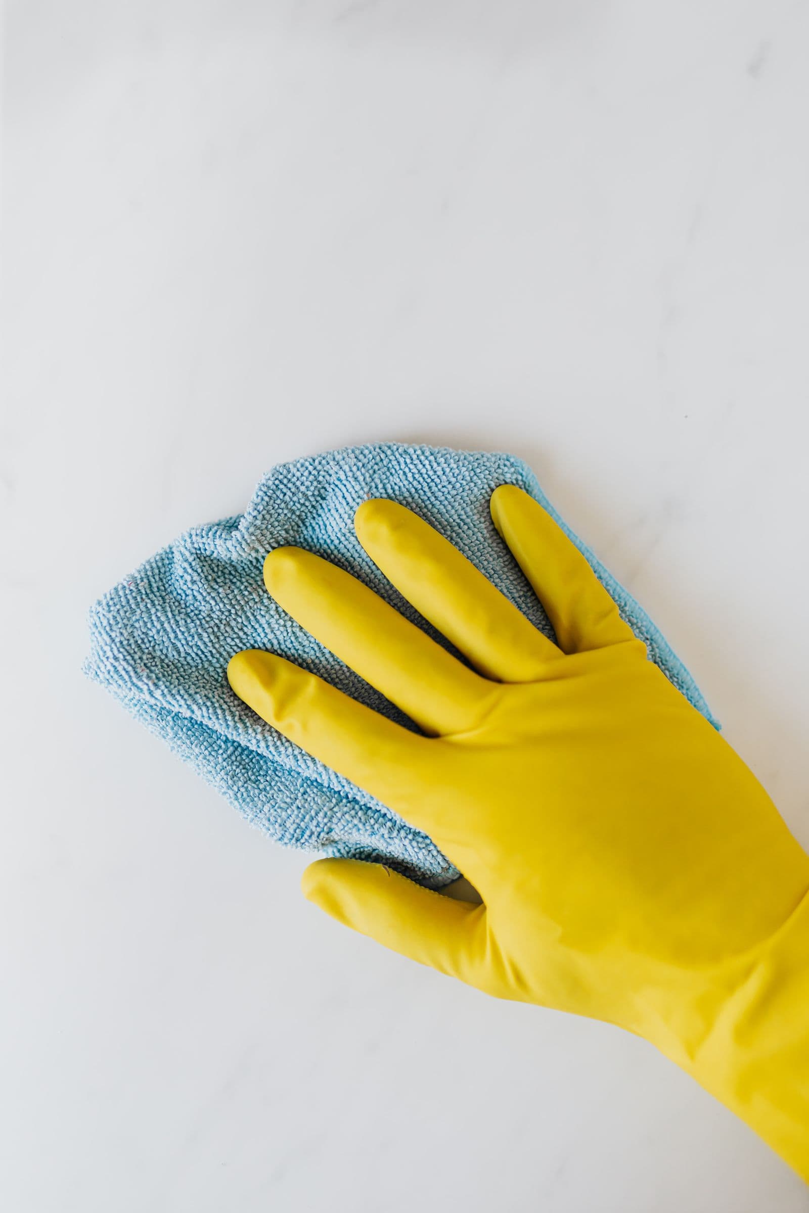 Main gantée passant une microfibre sur un plan de travail clair